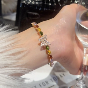 Dettaglio di un bracciale a farfalla in zircone dorato con gemme multicolore