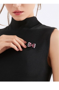 Close-up of a crystal butterfly brooch with purple rhinestones on a black turtleneck sweater