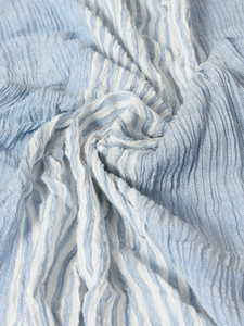 Macro shot of blue and white striped crinkle fabric texture on a casual men's scarf