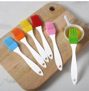 Detailed view of colorful silicone pastry brushes on a wooden board for BBQ and baking