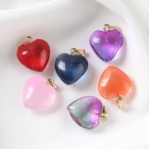 Close-up of heart-shaped acrylic pendants in multiple colors on white silk background
