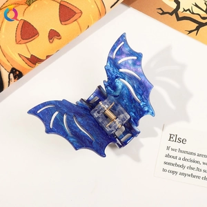 Detail shot of a blue glittery bat-shaped hair claw clip with Halloween themed decorations
