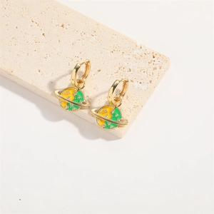 Detailed shot of saturn-shaped gold earrings with yellow-green enamel on a stone base