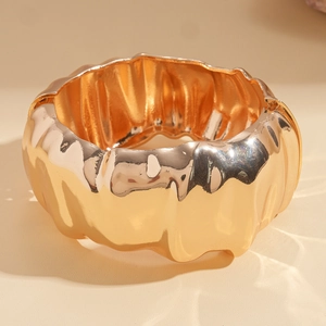 Macro detail of chunky gold cuff bracelet featuring irregular crumpled molten textures