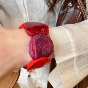 Close-up of a wide elastic resin bracelet with red and purple marble texture blocks