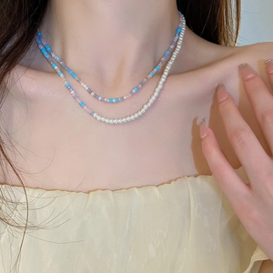 Detail of layered pearl and colorful gemstone necklace worn on the collarbone