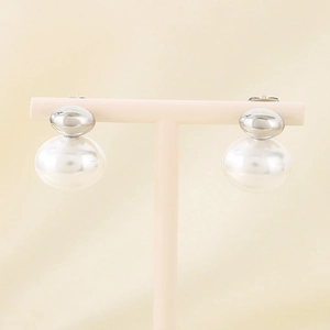 Close-up of vintage silver bow earrings with large white pearls on a display stand