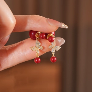 Detailed close-up of vintage gold-plated butterfly earrings with red pearls and zircon