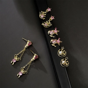 Gold animal earrings set with moon and star zircon studs on reflective black surface