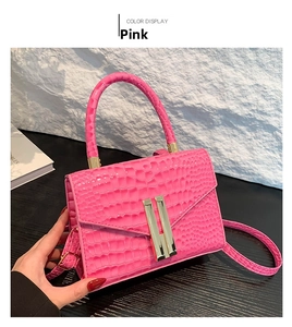 Detailed view of pink crocodile texture leather handbag with gold H-shaped metal buckle