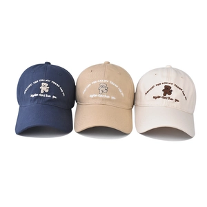 Detailed view of cotton baseball caps with bear embroidery in navy, khaki, and beige