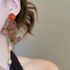 Close-up of vintage earrings featuring amber resin, chiffon petals and crystal drops