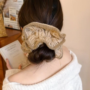 Detail of a khaki knitted flower scrunchie on a ponytail for an elegant hairstyle