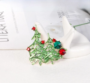 Detail of Christmas tree brooch with green enamel and rhinestones on ceramic hand prop