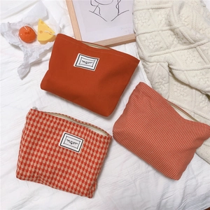 Detailed set of three orange houndstooth canvas cosmetic bags with metal zippers