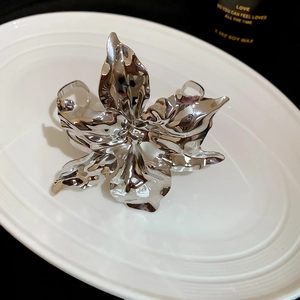 Detailed macro view of large silver metal flower cuff with textured liquid metal petals