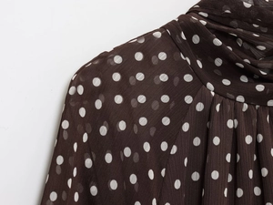 Macro detail of dark brown polka dot chiffon fabric featuring elegant neck pleats