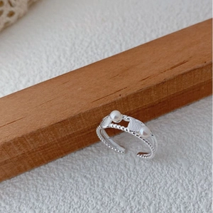 Macro detail of S925 silver shell ring with natural pearls on a wooden display