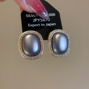 Close-up of vintage oval pearl earrings with gold plating and white zircon inlay