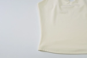 Detailed close-up of cream knit fabric texture and hemline of a summer tank top