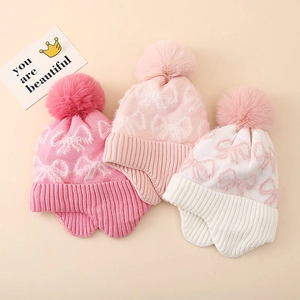 Close-up of winter knit earflap hats with pom-poms and bow jacquard patterns for girls