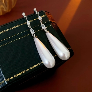 Detail of teardrop pearl tassel earrings resting on a vintage emerald jewelry box