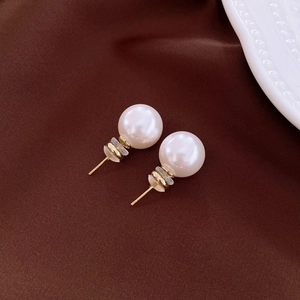 Macro view of round pink pearl studs with golden posts on elegant silk fabric