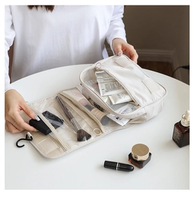 Beige hanging toiletry bag with multiple compartments showing organized cosmetics