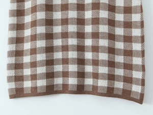 Detaillierte Makroansicht des braun-weißen Strickstoffs mit Karomuster-Textur