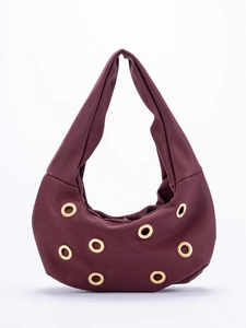 Close-up of the burgundy suede fabric and gold metal eyelets on the stylish hobo bag