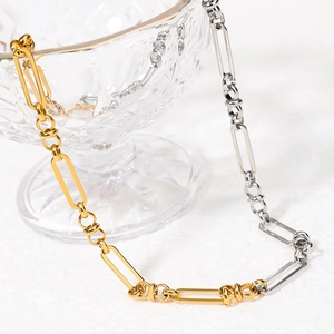 Minimalist gold and silver mixed Cuban link chain necklace on a glass texture background