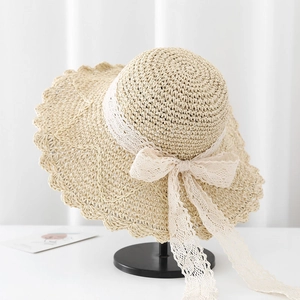 Detail of beige straw sun hat with white lace trim and bow knot on a display stand