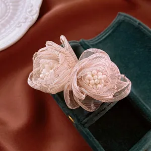 Elegant champagne tulle flower earrings with pearl centers on green velvet gift box