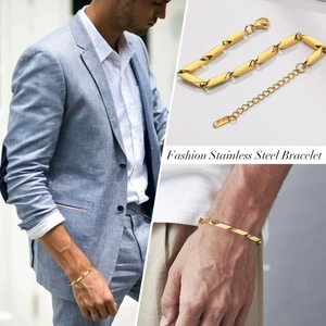 Detailed view of a gold stainless steel link bracelet on a model in a blue suit