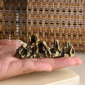 Macro detail of a traditional brass mountain-shaped paperweight with wax-casting texture