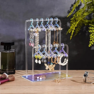 Detailed view of iridescent acrylic earring holder with mini hangers on a wooden desk