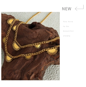 Detail of 18K gold-plated chunky Cuban link necklace with sunburst charms on wood