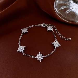 Close-up of adjustable silver bracelet with five snowflake zircon pendants on satin