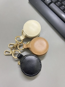 Close-up of three circular leather jewelry storage pouches with gold metal hooks and zippers