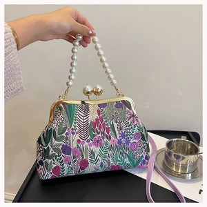 Details der Blumenstickerei und Perlengriff an einer eleganten Vintage-Handtasche