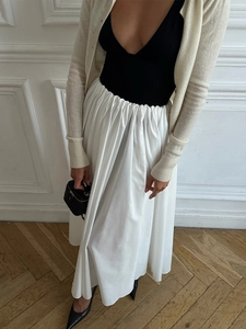 Elegant high-waisted white maxi skirt paired with black top and quilted leather handbag