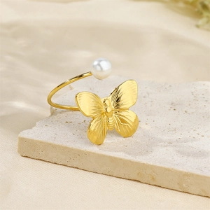 Detail of 18k gold plated bow ring with pearl on beige stone and silk background