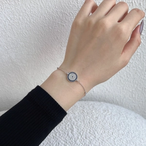 Makroaufnahme des silbernen Evil-Eye-Armbands mit blau-weißen Zirkonsteinen am Handgelenk