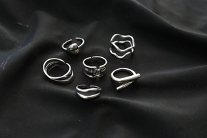 Detail of a 6-piece silver alloy ring set featuring minimalist heart and wave designs