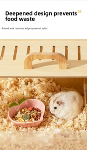 Pink peach-shaped ceramic hamster bowl with high edges shown in a cozy wooden cage habitat