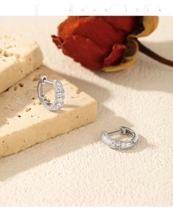 Detail of silver hoop earrings with clear stones on stone base with a rose