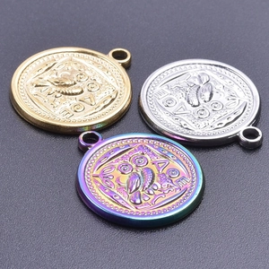 Macro shot of owl coin pendants in gold, silver, and rainbow steel with Greek relief