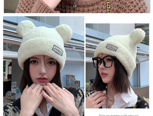 Detail of white plush trapper hat with cute bear ears and brand label for winter