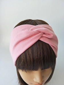 Detail of pink knitted ribbed headband with twist design shown on model's head
