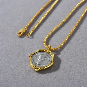 Detail of two-tone gold keel chain with silver coin pendant featuring Elizabeth II relief